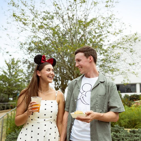 Two Guests enjoying food and beverages near the Spaceship Earth attraction in Epcot
