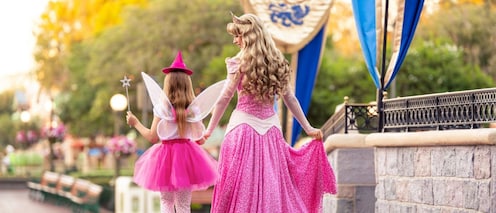 Princess Aurora walking with a young girl dressed as a fairy godmother.