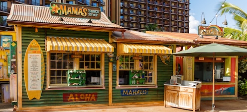 The exterior of Mama's Snack Stop, a quick-service venue with weathered green paint and yellow-striped awnings