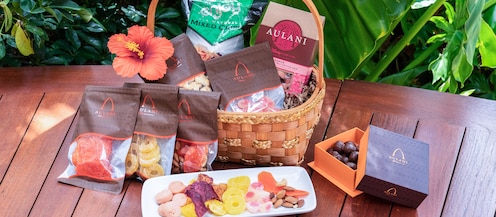 A gift basket of packaged tropical treats, topped with a flower