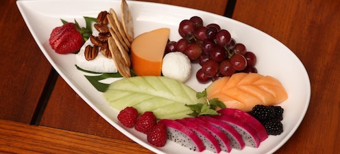 A platter features a cheese arrangement surrounded by slices of berries, melons and other fruits