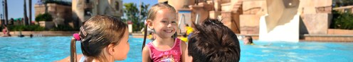Un par de niñas disfrutan de la piscina junto a su padre en el Caribbean Beach Resort