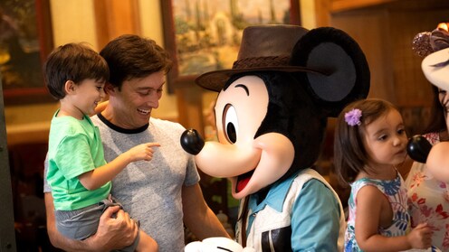 Mickey Mouse, dressed as an explorer, interacts with Guests