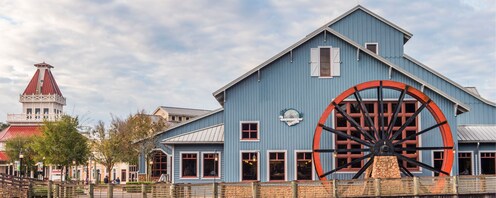 Disney’s Port Orleans Resort Riverside, a farm style building with a large water wheel and a wooden bridge, by the banks of the Sassagoula River