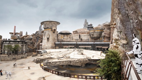 Millennium Falcon docked in Star Wars, Galaxy’s Edge with a stormtrooper standing on a balcony nearby