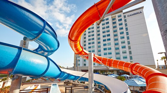 Two tall, tubular, winding slides with water to splash in at their bottoms