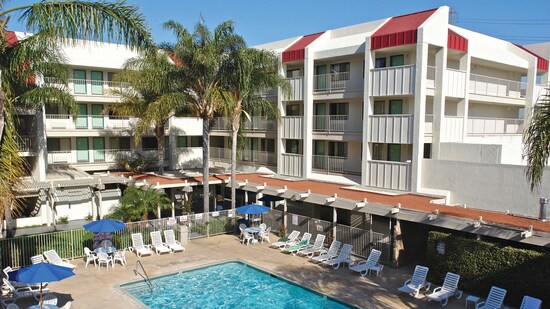 Outdoor furniture lining a pool and, beyond, the buildings of the Motel 6 Anaheim Maingate