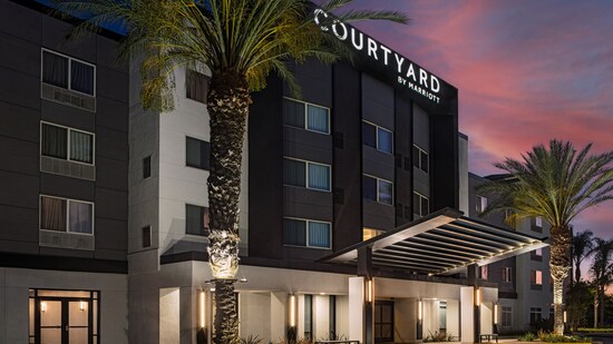 Landscaped with palm trees, the modern exterior of the Courtyard by Marriott Anaheim Resort.