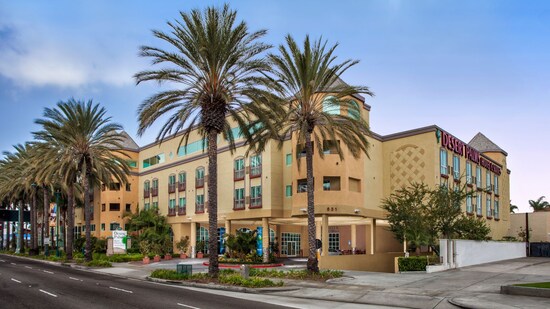The exterior of the Desert Palms Hotel & Suites Anaheim Resort with several palm trees