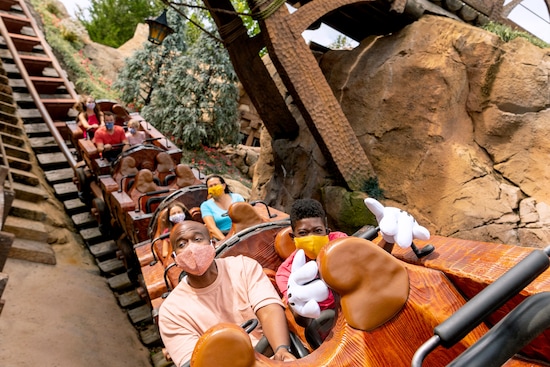A father and son and other families enjoy a ride on the Seven Dwarfs Mine Train at Magic Kingdom Park.