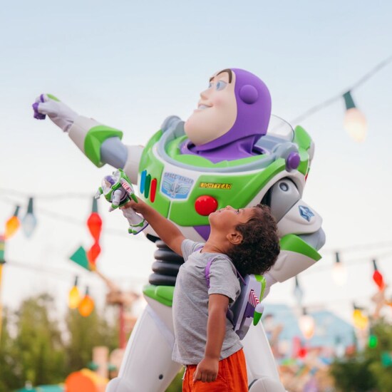 A boy standing next to Buzz Lightyear in Toy Story Land