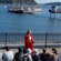 Wearing a red cloak, a performer speaks to a group of Guests