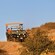 An open air Hummer filled with passengers traveling through rugged terrain
