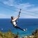 A woman zip lining near an ocean