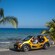 4 passengers in an open air buggy stopped at a tropical beach