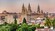 An ornate Gothic cathedral with 3 steeples towering over a European city