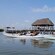Pessoas sentadas em caiaques próximos a uma doca com uma cabana tiki e um barco