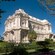A historic building with columns and balconies stands tall behind a fence