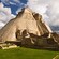 A stone Mayan pyramid with a tall staircase that leads to the top