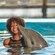 A young girl smiles as a dolphin kisses her on the cheek