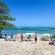 People sunbathing, lounging under umbrellas and participating in watersports at a tropical beach