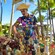 A man in a straw hat looking over a cart filled with handmade necklaces, figurines and other souviners