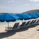 Outdoor recliners and umbrellas line the sand on a Caribbean beach, facing the water