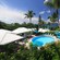 A beach setting with a circular swimming pool surrounded by tropical foliage
