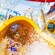 A smiling young woman watersliding with arms across her chest and feet first into the Splash Zone