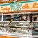 A sign with a portrait of Daisy Duck hangs above a quick service counter with fruit, salads and bakery items