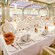 A brightly lit, art deco-styled dining room with tables set for a fancy dinner