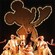 Dancers in sparkling tuxedos and top hats pose on stage with Goofy at The Golden Mickeys
