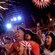A audience dressed as Pirates of the Caribbean characters marvel at the fireworks going off overhead