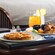 On a table in a stateroom, a tray with a personal size pepperoni pizza, chicken wings and 2 drinks