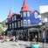 A street with buildings, pedestrians, potted flowers, trees and more