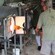 A man fashions a glass mug near a kiln while a woman assists him