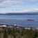 A town wedged between a forest and a bay with a ship and a bridge