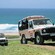 A pair of Island Safari all terrain vehicles roll uphill on a dirt road near the ocean