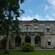 A large, 2 story stone building with an open balcony above the main entrance
