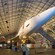 A Concorde jet plane sits inside an aircraft hangar as a man points to its cone shaped nose
