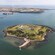 An aerial view of tiny Spike Island surrounded by water with a land mass nearby