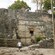 A man walking by the Kohunlich Mayan Ruins in an outdoor area featuring trees