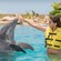 A dolphin nuzzles a woman's hand