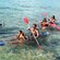 Pairs of children and adults paddling the waters in transparent kayaks