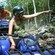 A girl on a stopped ATV smiles as she points to something within the forest