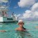4 people stand on a boat while a woman smiles in the water