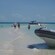 Men walk across an sand bar towards an inflatable boat with a rigid hull