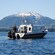A fishing cruiser on the water in front of snowcapped mountains