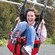A woman smiles as she comes in for a zip line landing on a pebble beach