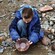 A young boy pans for gold on the rocky bank of a creek